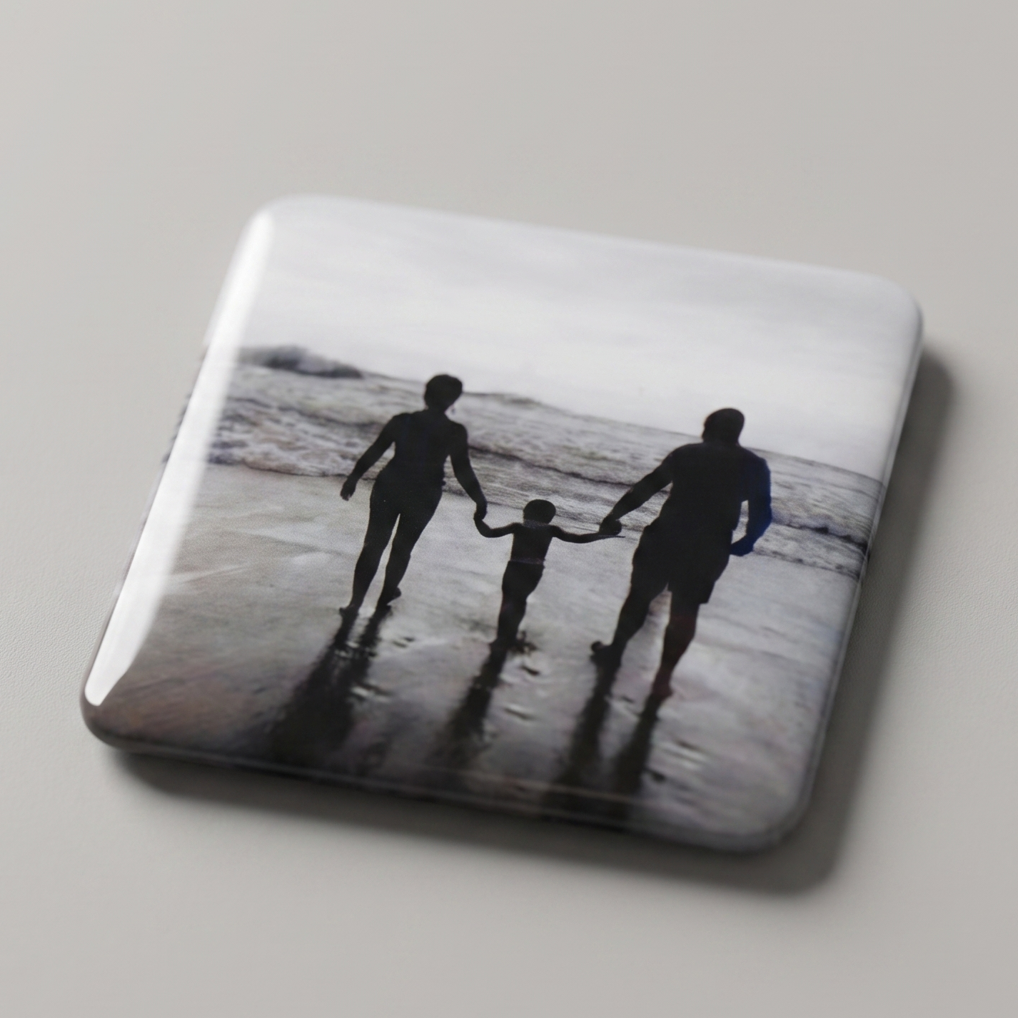 Ímã com foto em preto e branco de família de mãos dadas caminhando na beira do mar