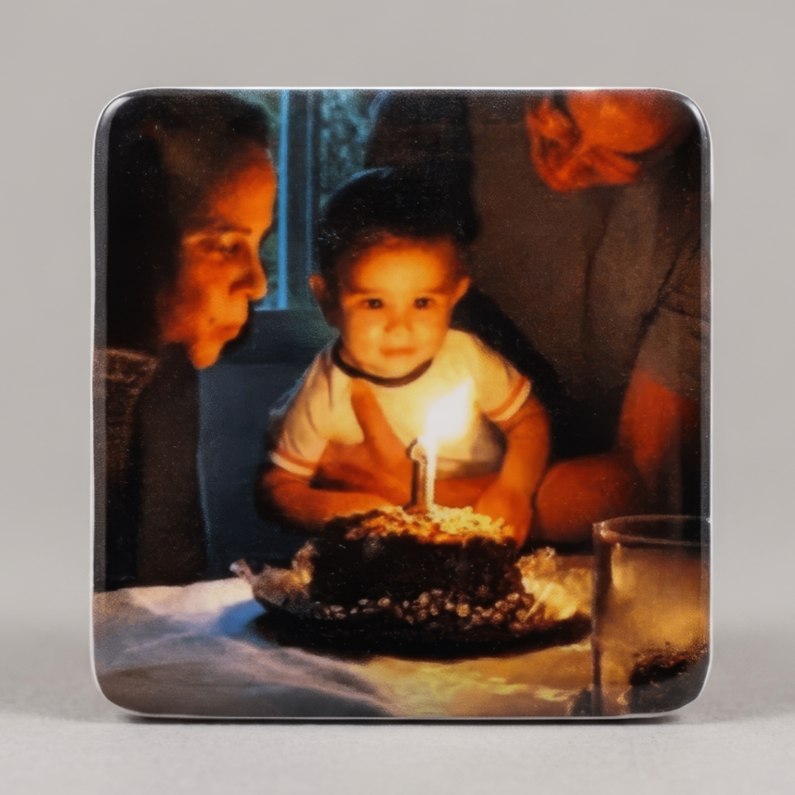 Ímã com foto de bebê iluminado pela vela de aniversário de um ano em bolo de chocolate